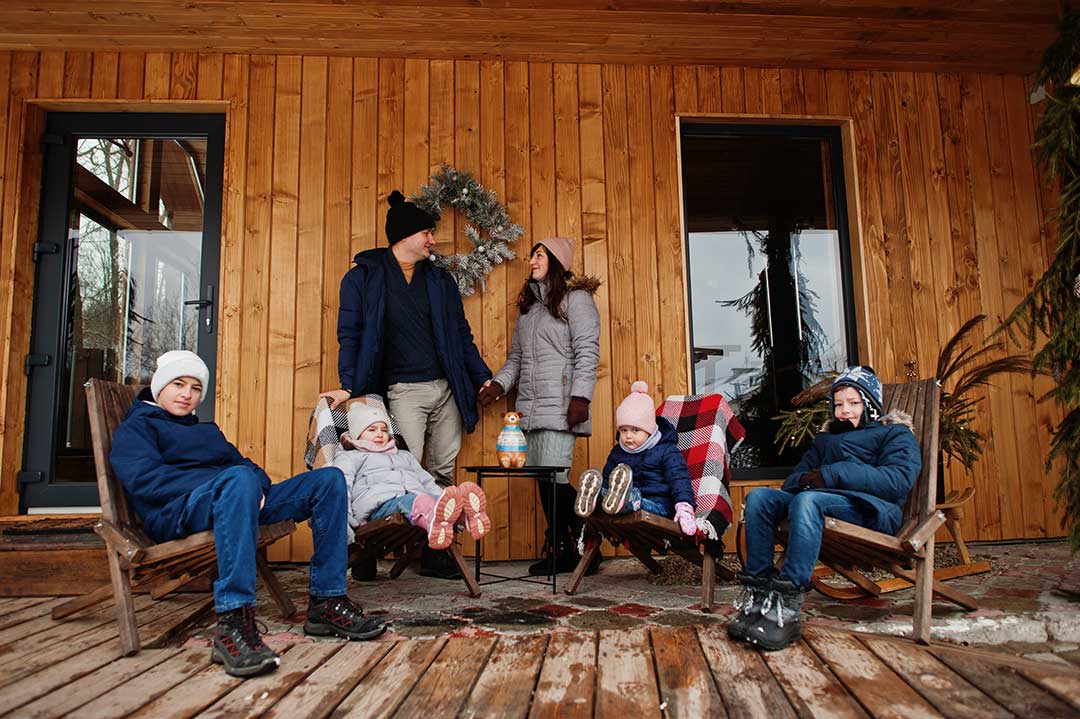 Green-Tourism-big-young-family-with-four-kids-terrace-wooden-house-winter-day