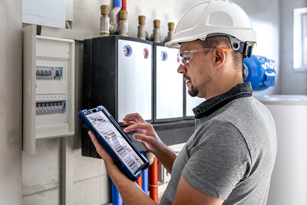 Green-Tourism-electrical-technician-looking-focused-while-working-switchboard-with-fuses